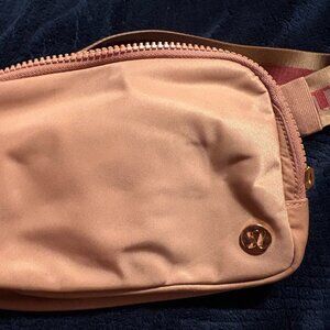 Lululemon Belt Bag 1L Wordmark in medium pink (forgot name) with rose gold.
